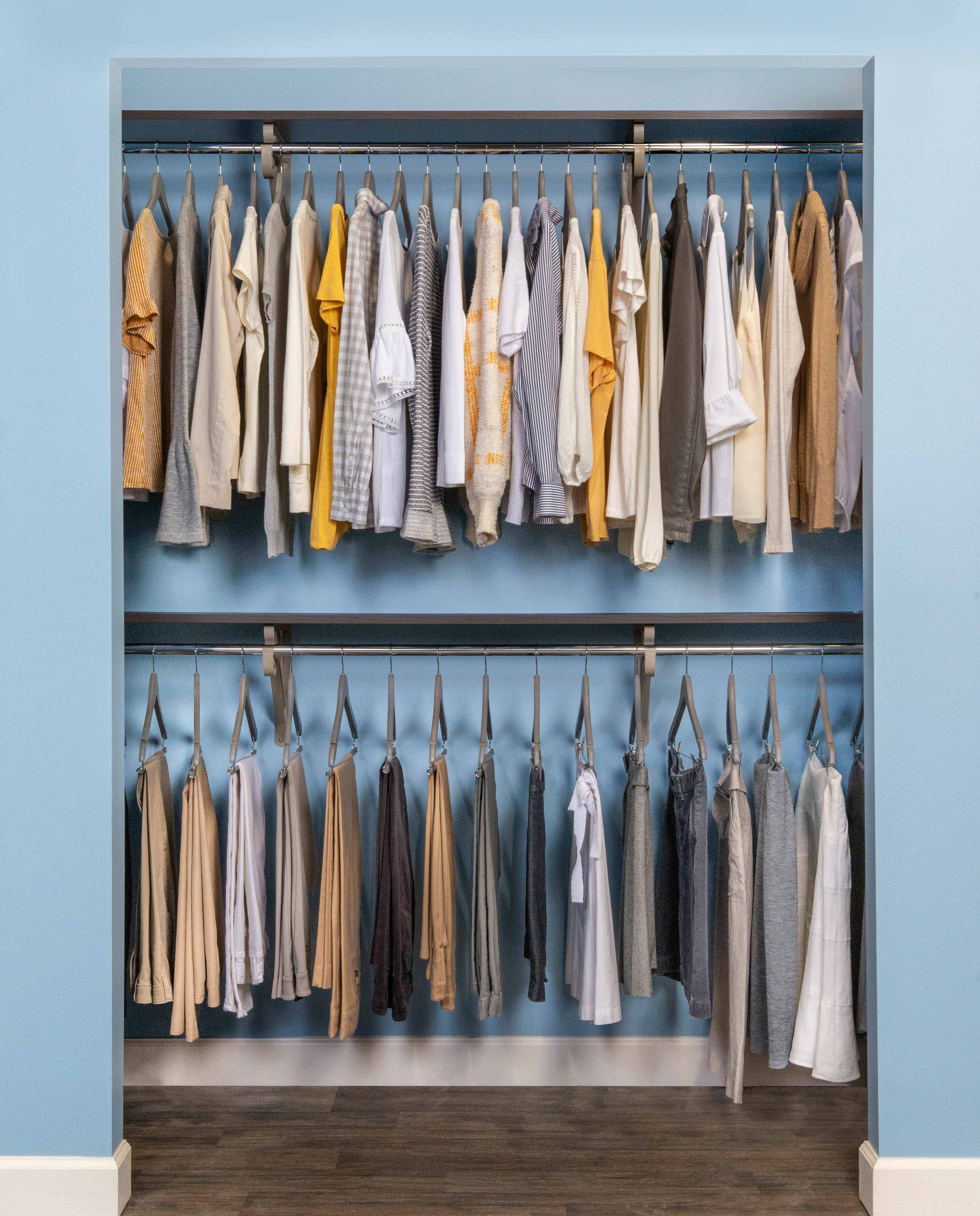 VUE Reach-In Closet in Chocolate Pear with double hang, clothes, hangers with blue wall.