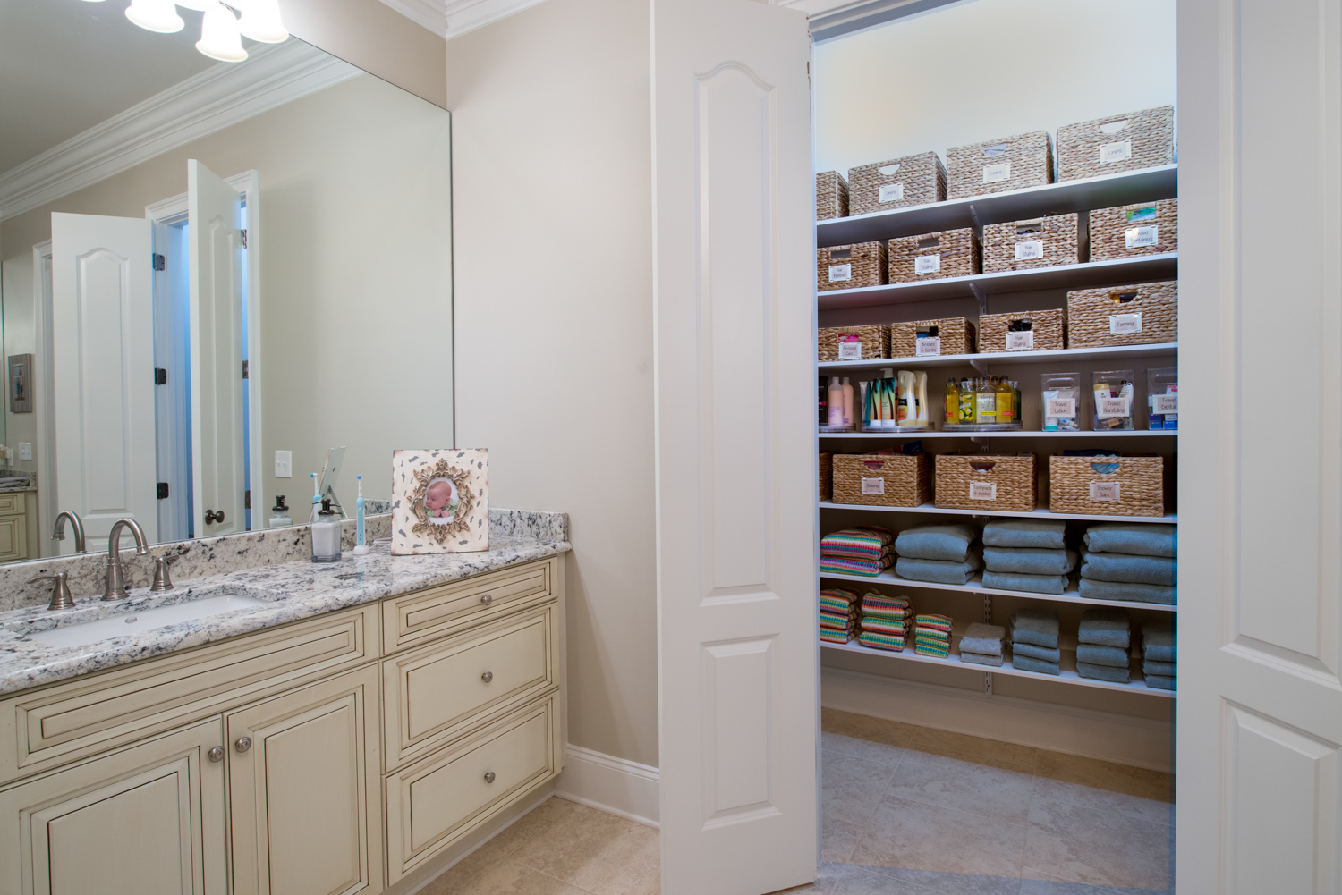 Bathroom Organization with freedomRail storage solution with personal care products in baskets, bath towels, and body care.