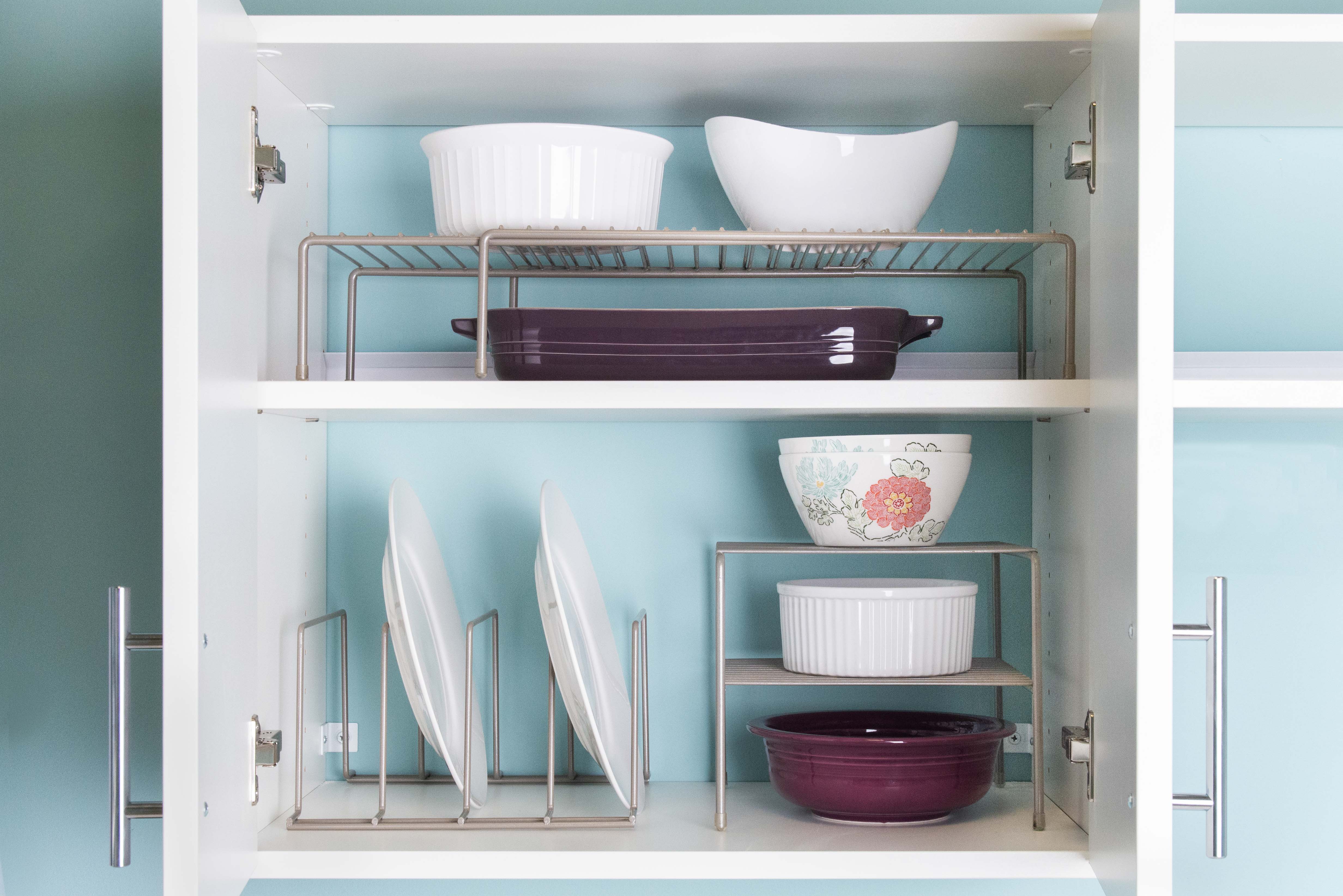 Kitchen Organizers in White with dinnerware stacked vertically, utilizing space in cabinet.