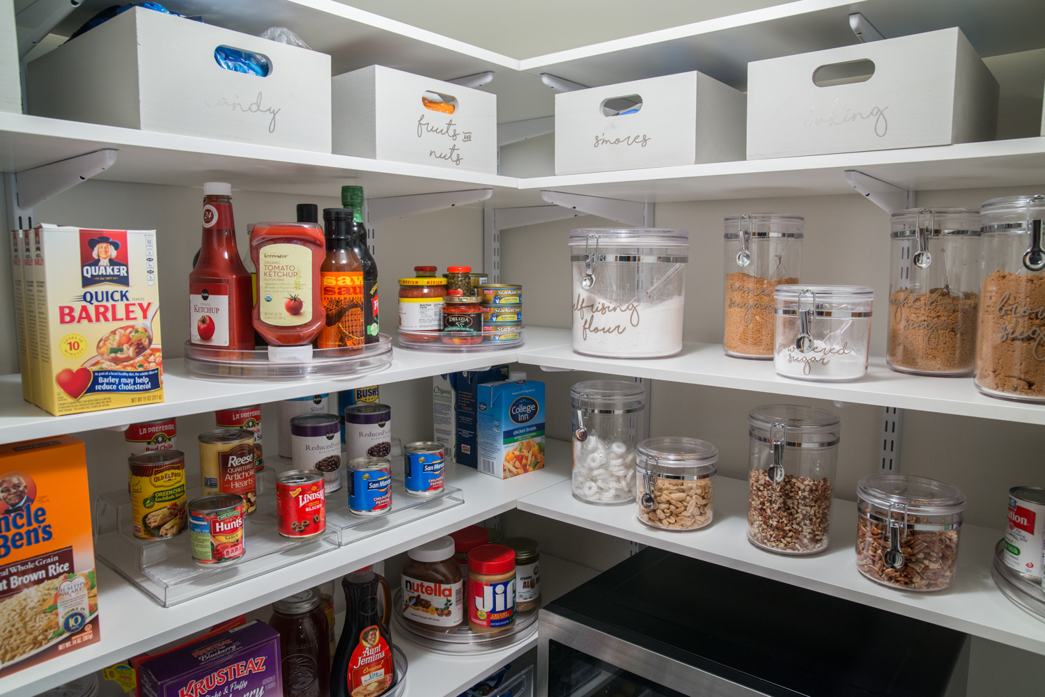 freedomRail Pantry in White with Uncle Ben's Brown Rice, Quaker Quick Barley, Ketchup, JIF, Krusteaz, and storage bins inside of pantry.