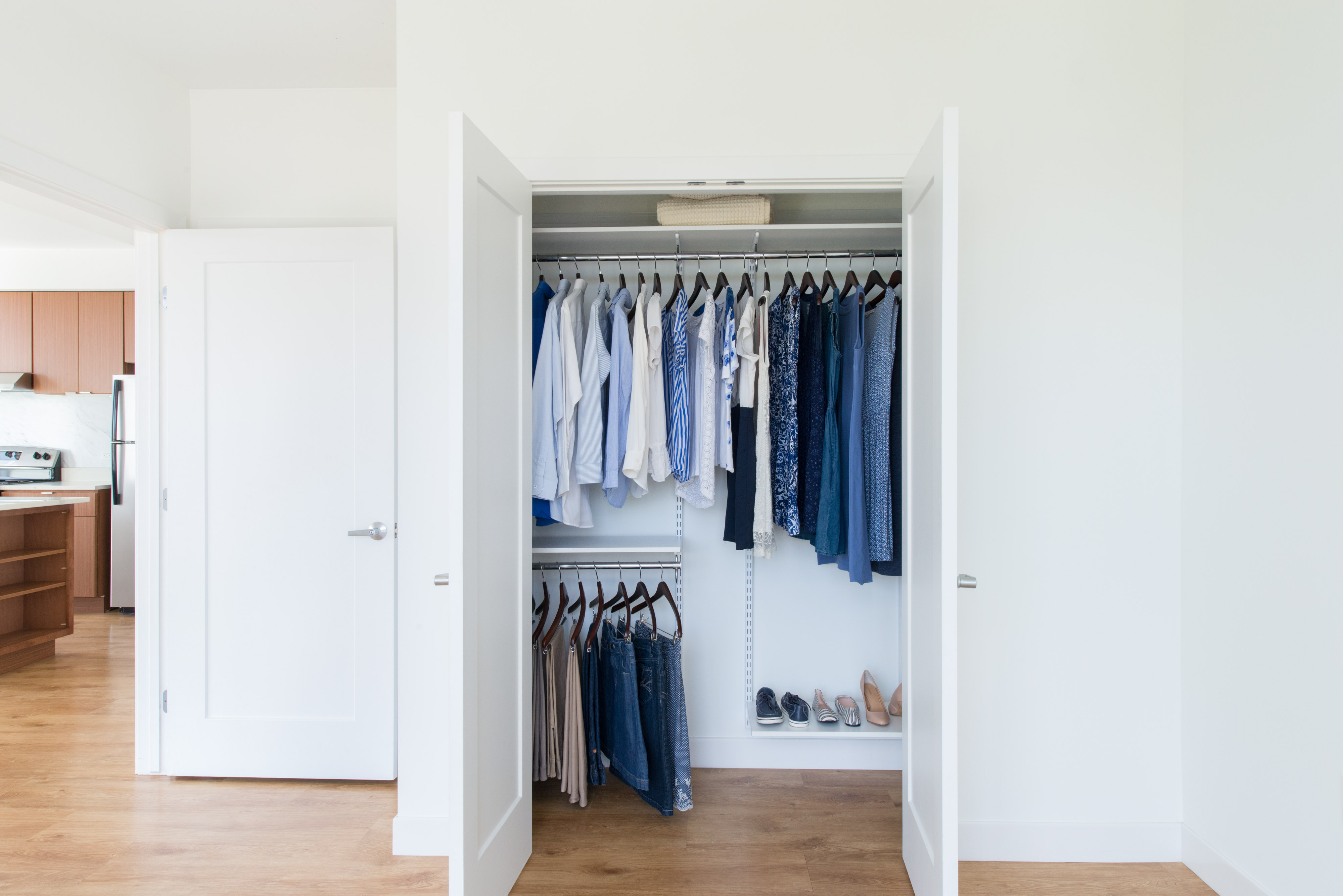 freedomRail Reach-in Closet in White with clothing inside an apartment.