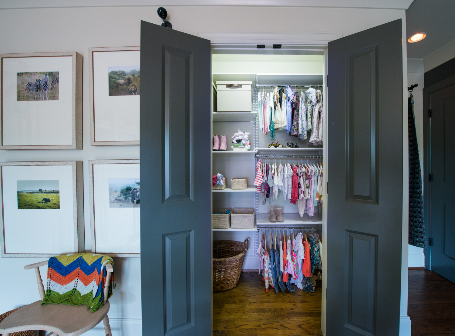 Nursery freedomRail Reach-in Closet in White with baby clothes and baskets.